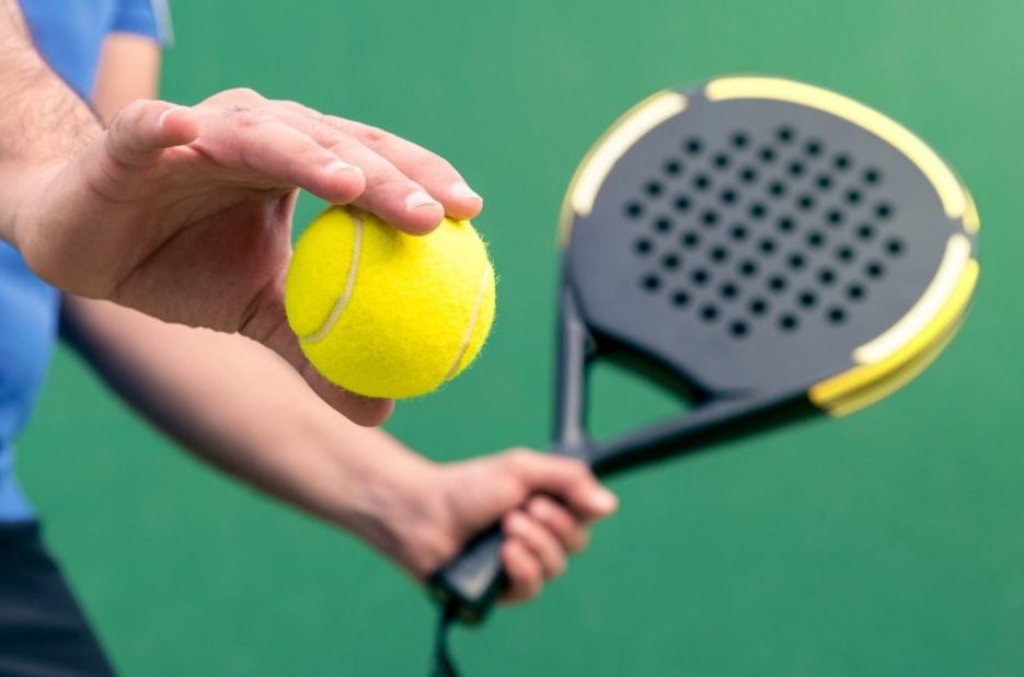 Professional monitor of padel holding black racket on green court. Game concept