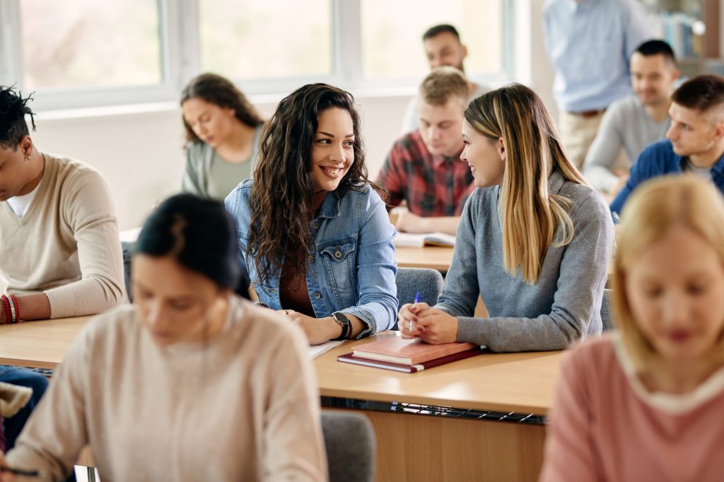 Happy female students talking during a class at university classroom.